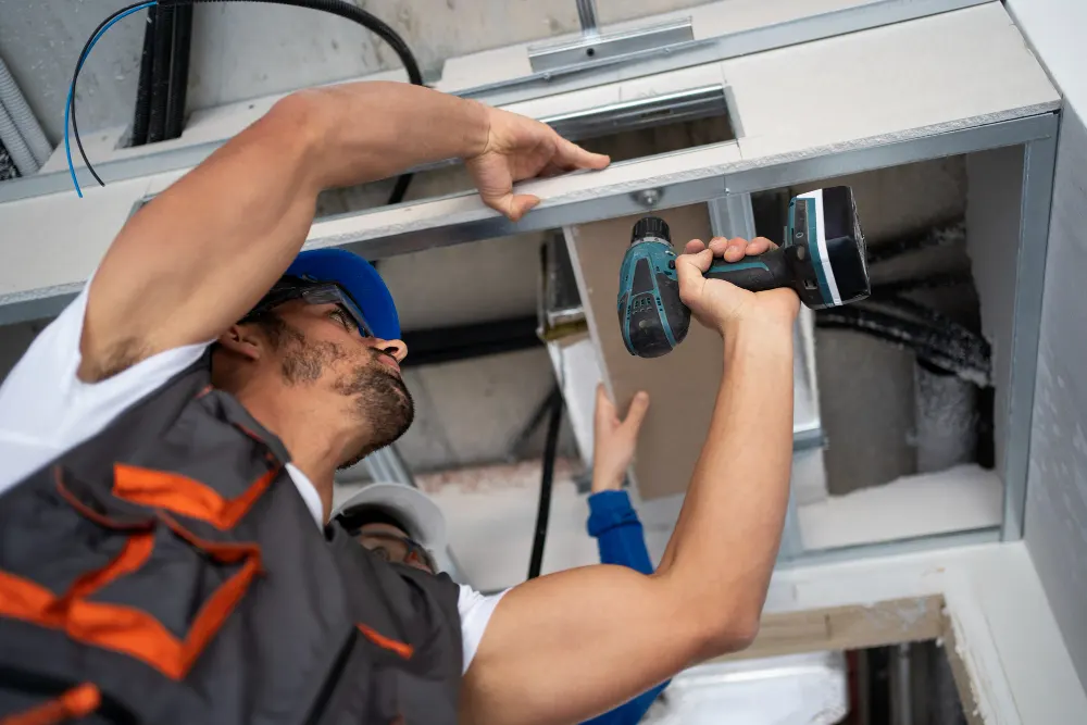 J-PAC Construction worker installing an access hatchway frame and ceiling opening during interior basement improvements