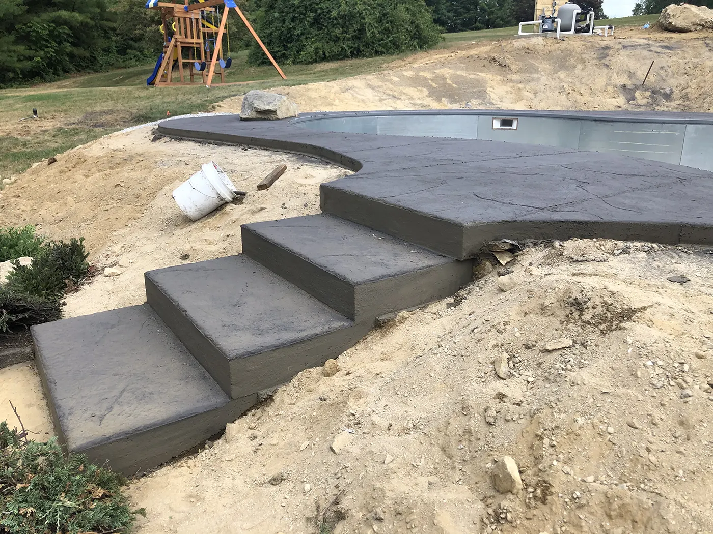 J-PAC Construction concrete stairs with stamped old granite texture tops in charcoal integral color leading to a pool deck