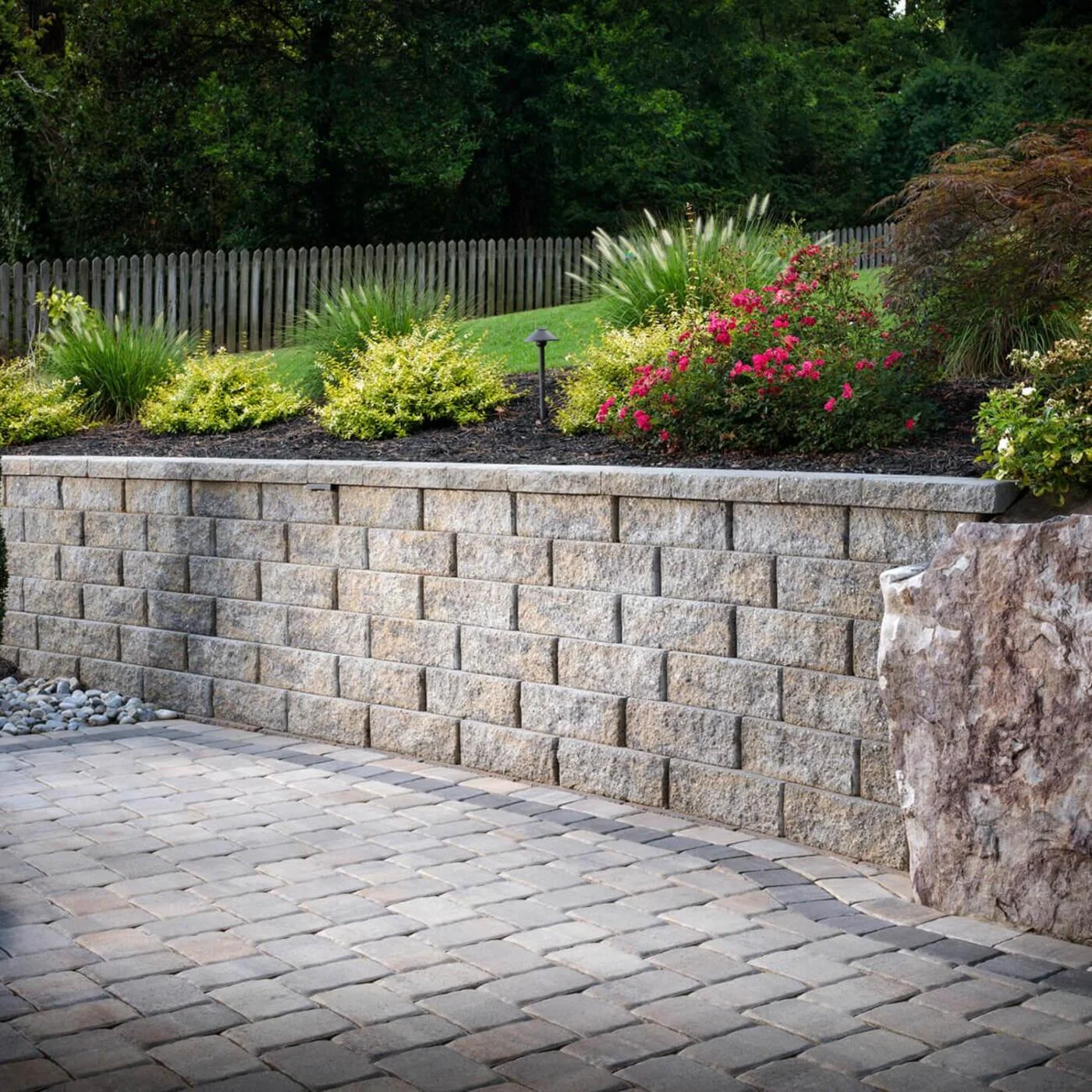 Segmental block retaining wall with a planted bed above a paver surface
