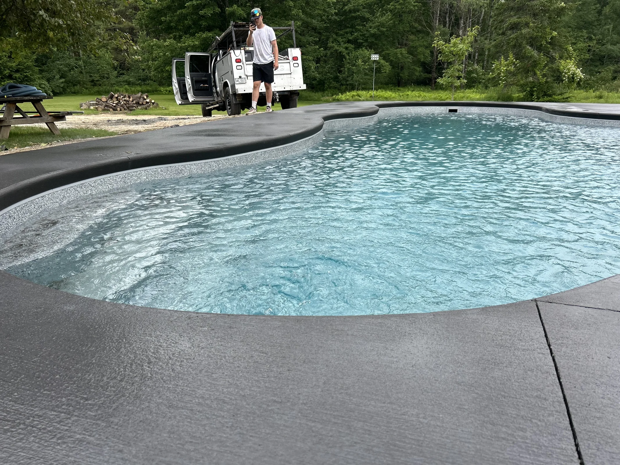 J-PAC Construction gray concrete pool deck with poured cantilever coping around a freeform pool in Maine