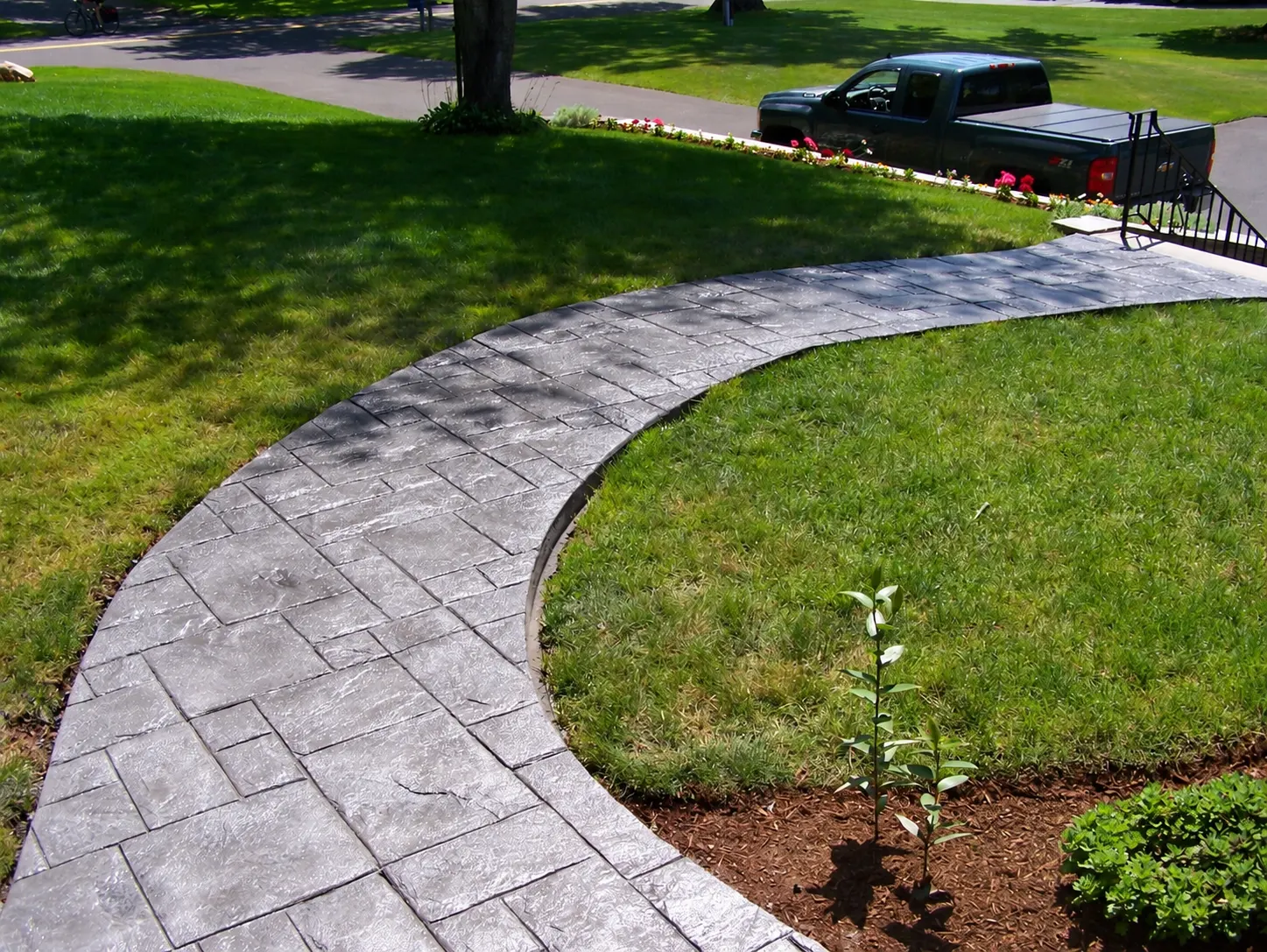 J-PAC Construction curved stamped concrete walkway with random slate pattern and charcoal release border leading to driveway in Maine