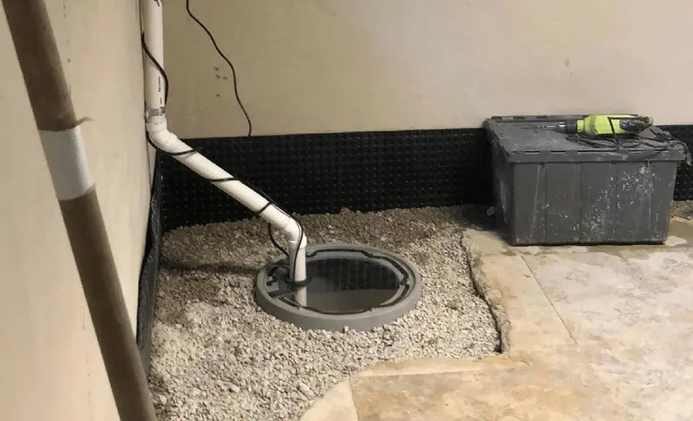 Sump pump installation with a basement drainage pit and discharge pipe for removing excess wate