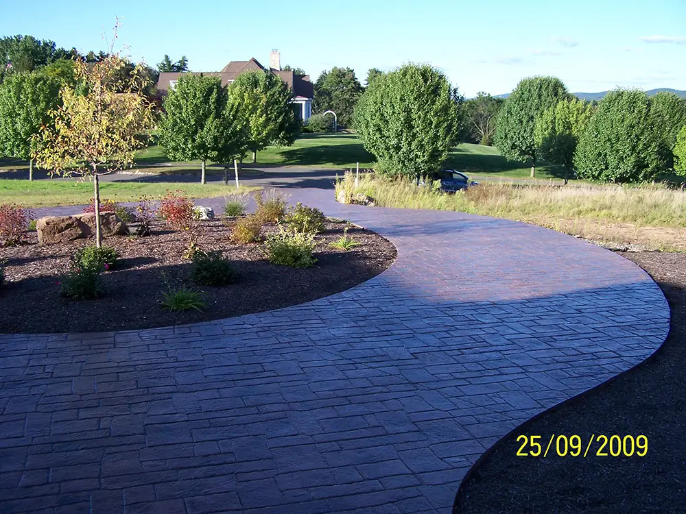 Repaired curved stamped concrete driveway with landscaped beds - J -Pac Construction