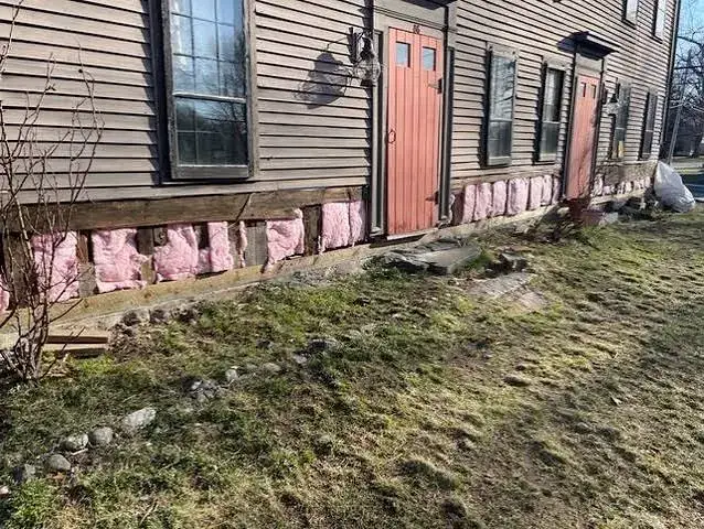 Exterior wood framing rot repair on a low foundation wall with exposed insulation before rebuilding